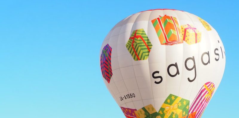 Vibrant hot air balloon with gift designs sailing under a clear blue sky.